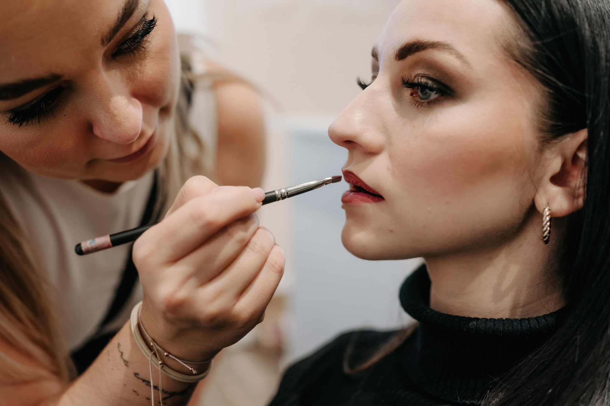 Visagistin trägt Lippenstift auf Visagistin trägt während einer Beauty-Behandlung Lippenstift auf einen Kunden auf.