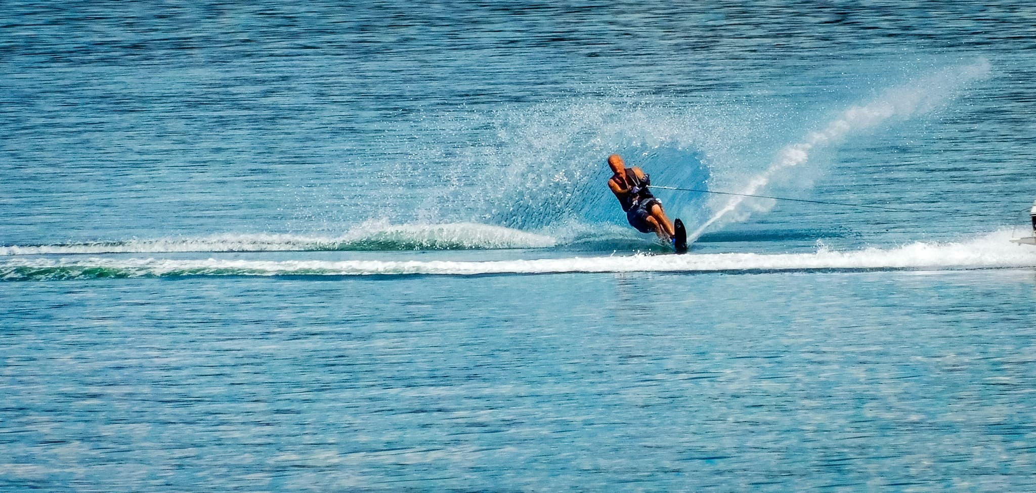 Wakeboarder Carving Ocean Wave Wakeboarder performing a carving maneuver on blue ocean water with white wave spray.