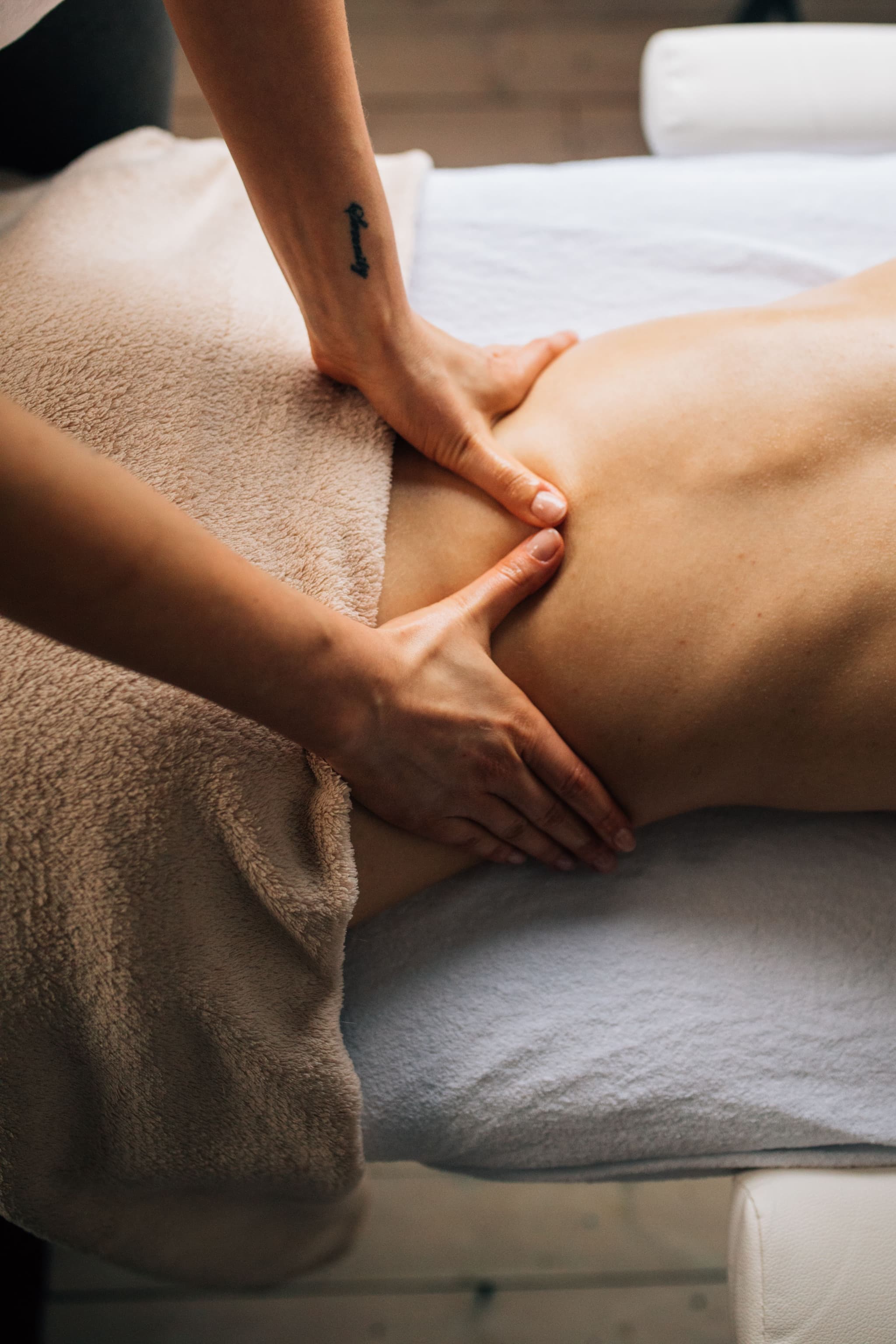 Back Massage Therapy Session Massage therapist using hands to knead a client's lower back muscles.