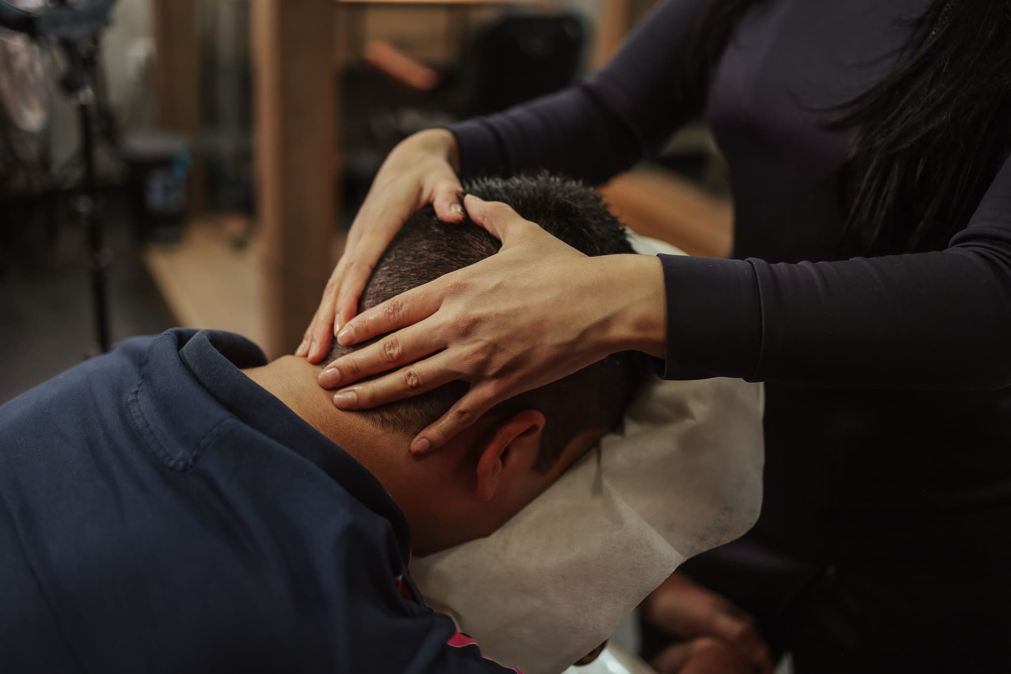 Head and Neck Massage in Salon Hairdresser massaging a seated client's head and neck in a salon.