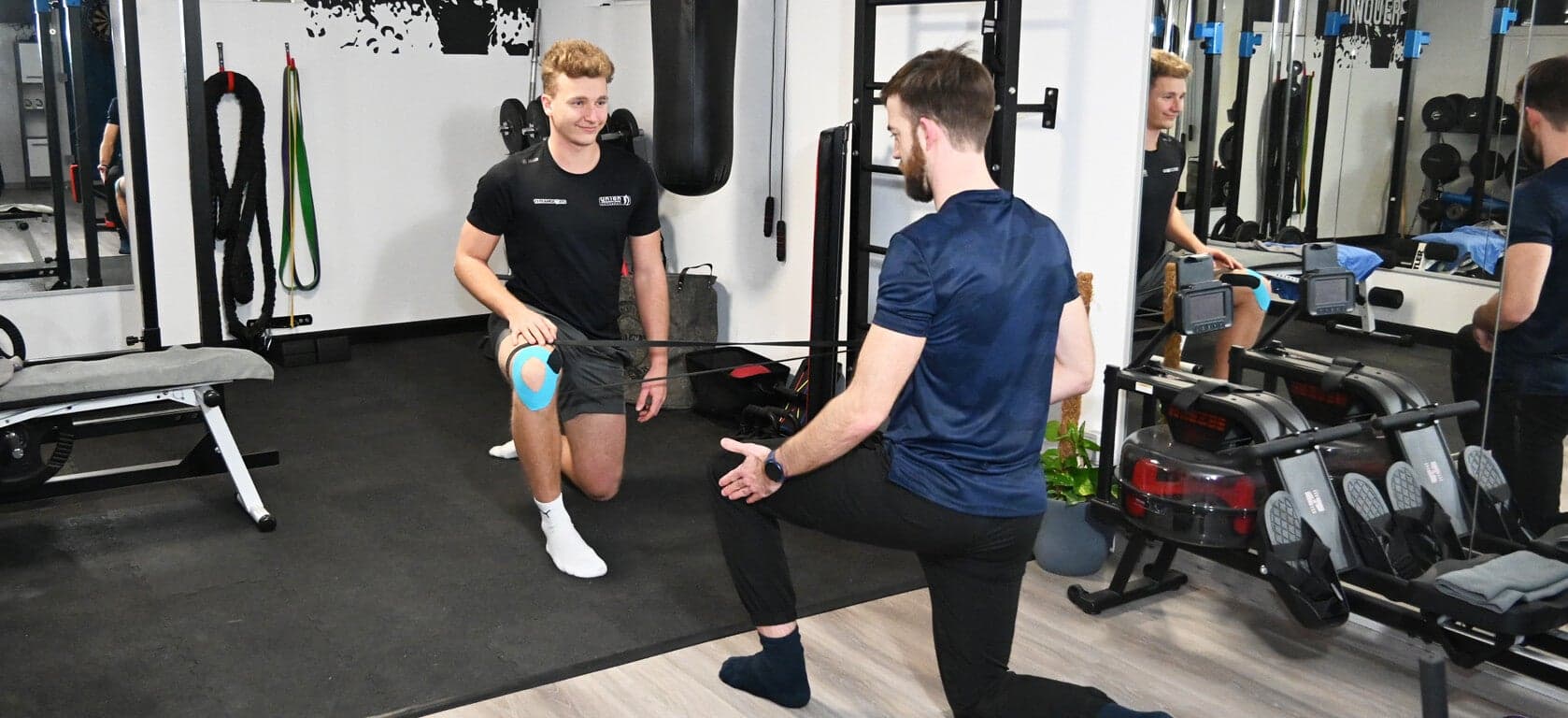 Leg Stretch with Resistance Band and Trainer Trainer assists client with a leg stretch using a resistance band in the gym.