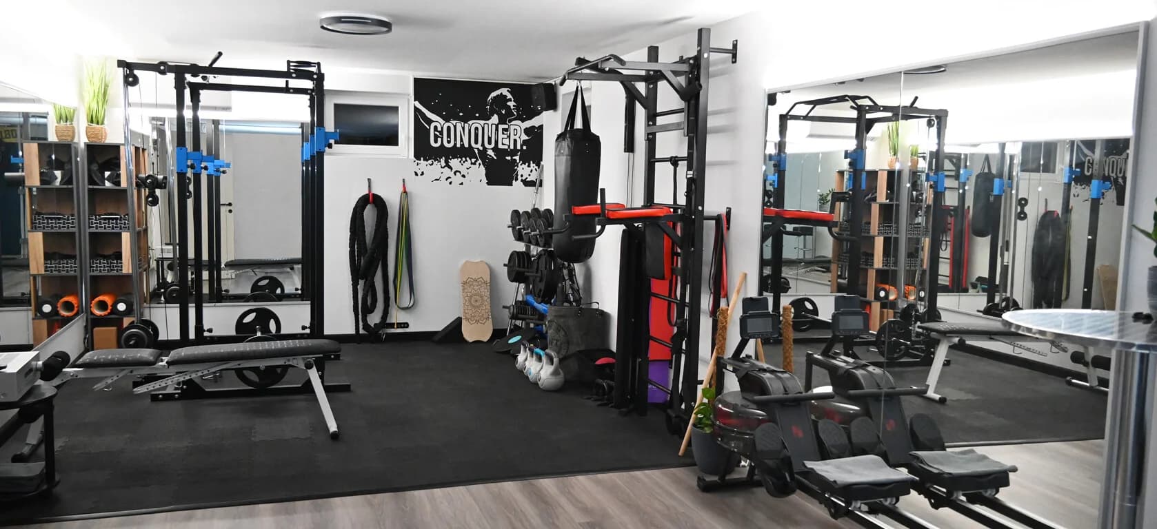 Home Gym with Power Rack and Heavy Bag Home gym with power rack, heavy bag, weights, and mirror wall.