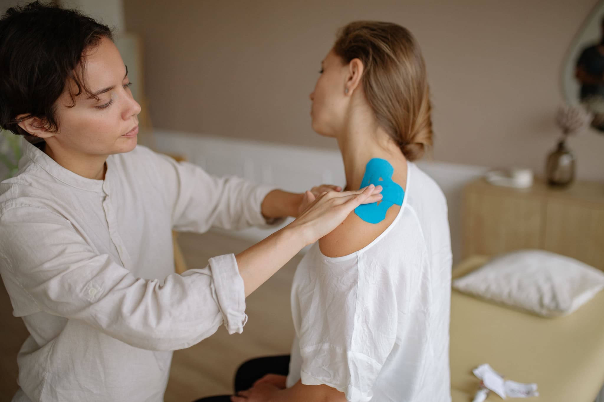 Healthcare Provider Applying Therapeutic Patch Healthcare provider applying a blue therapeutic patch to a patient's shoulder during a treatment session.