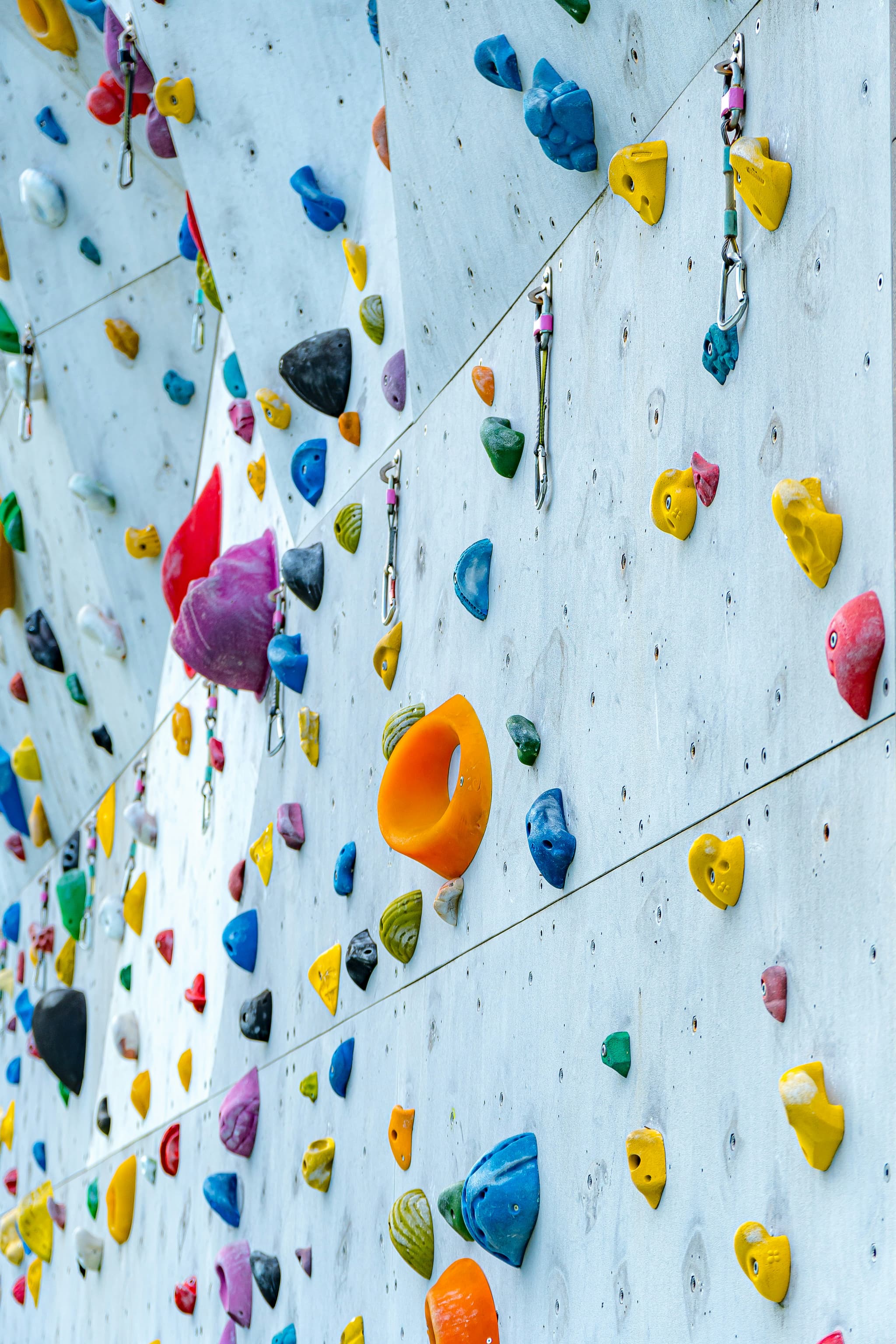 Indoor Climbing Wall With Colorful Holds Indoor climbing wall with colorful handholds and safety ropes attached to the surface.