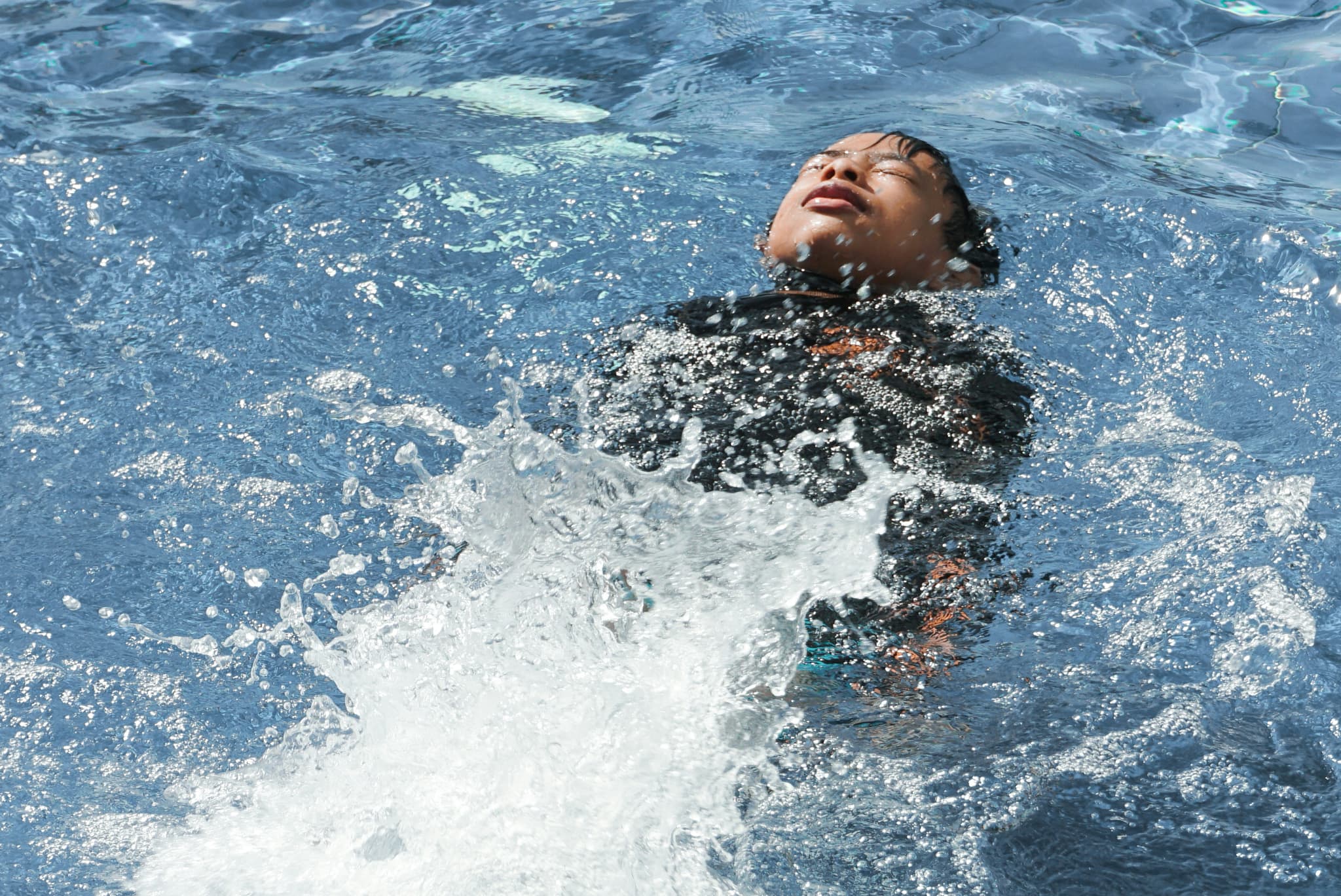 Person Floating in Pool Water Person floating on their back in a swimming pool with clear blue water.