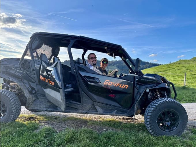 Off-Road Buggy on Grassy Hillside Two people sitting in an open-sided off-road buggy on a grassy hillside.