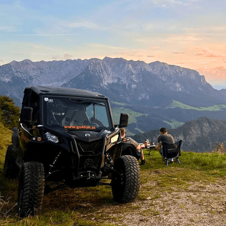 Off-Road Buggy at a Mountain Viewpoint at Sunset Off-road buggy parked on a mountain ridge while people relax at sunset.