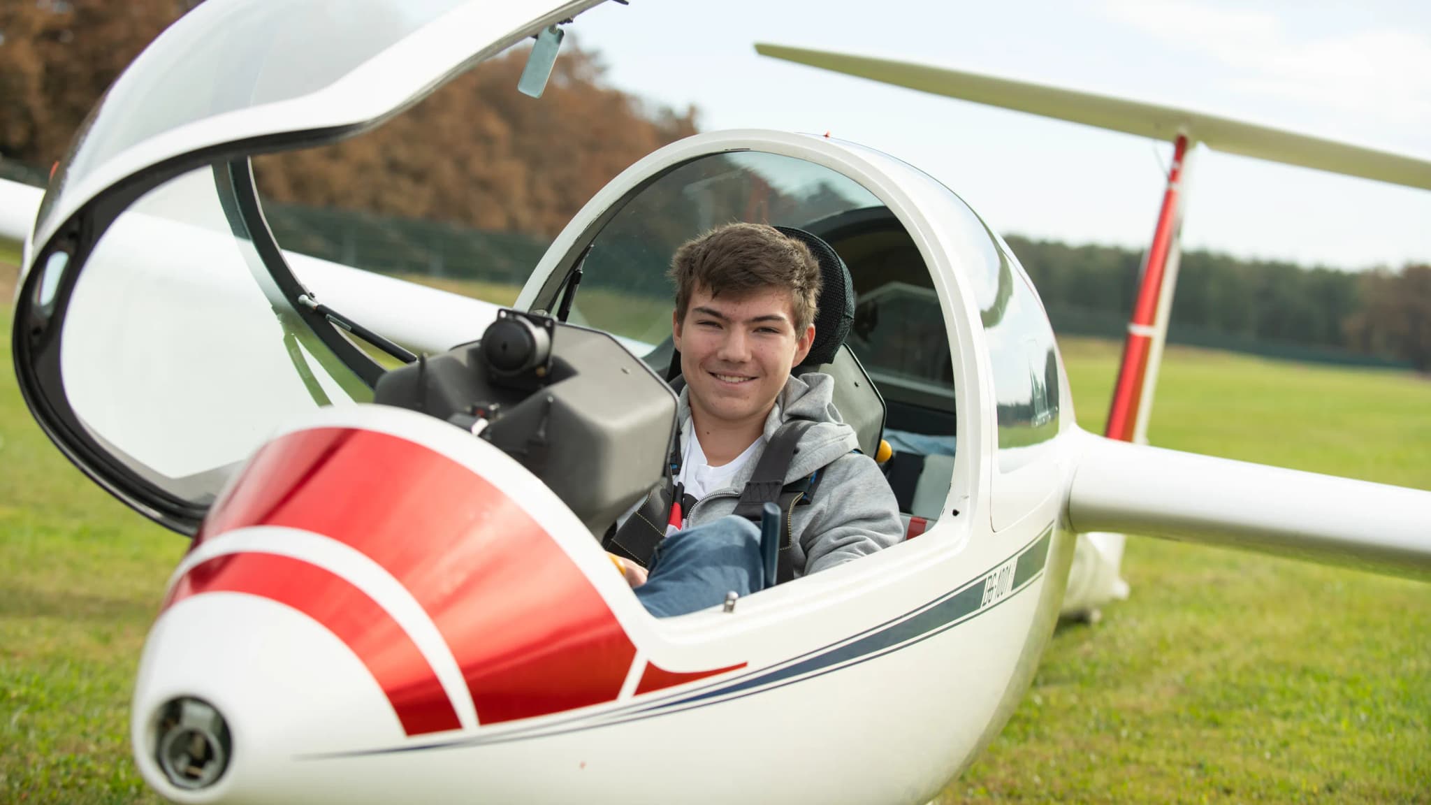 Smiling Pilot in Glider Cockpit Young pilot smiling in the cockpit of a glider on a grass airfield.