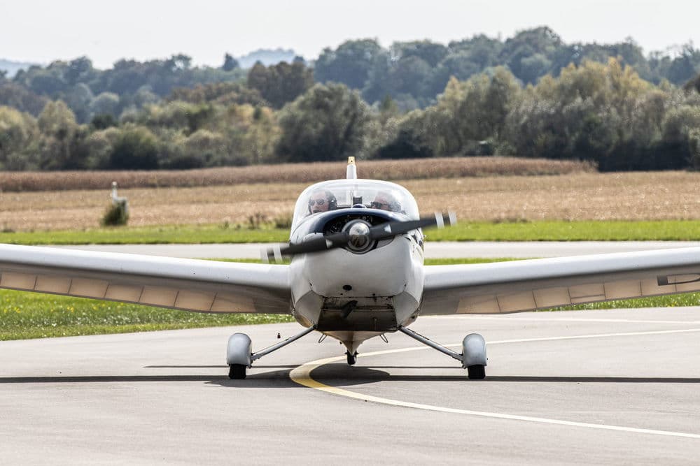Small airplane on the runway Small propeller airplane taxis with two people in the cockpit on the runway.