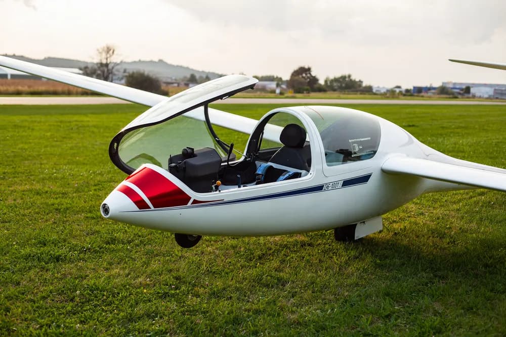 Glider on a grass airfield White glider with an open canopy on a grass airfield.