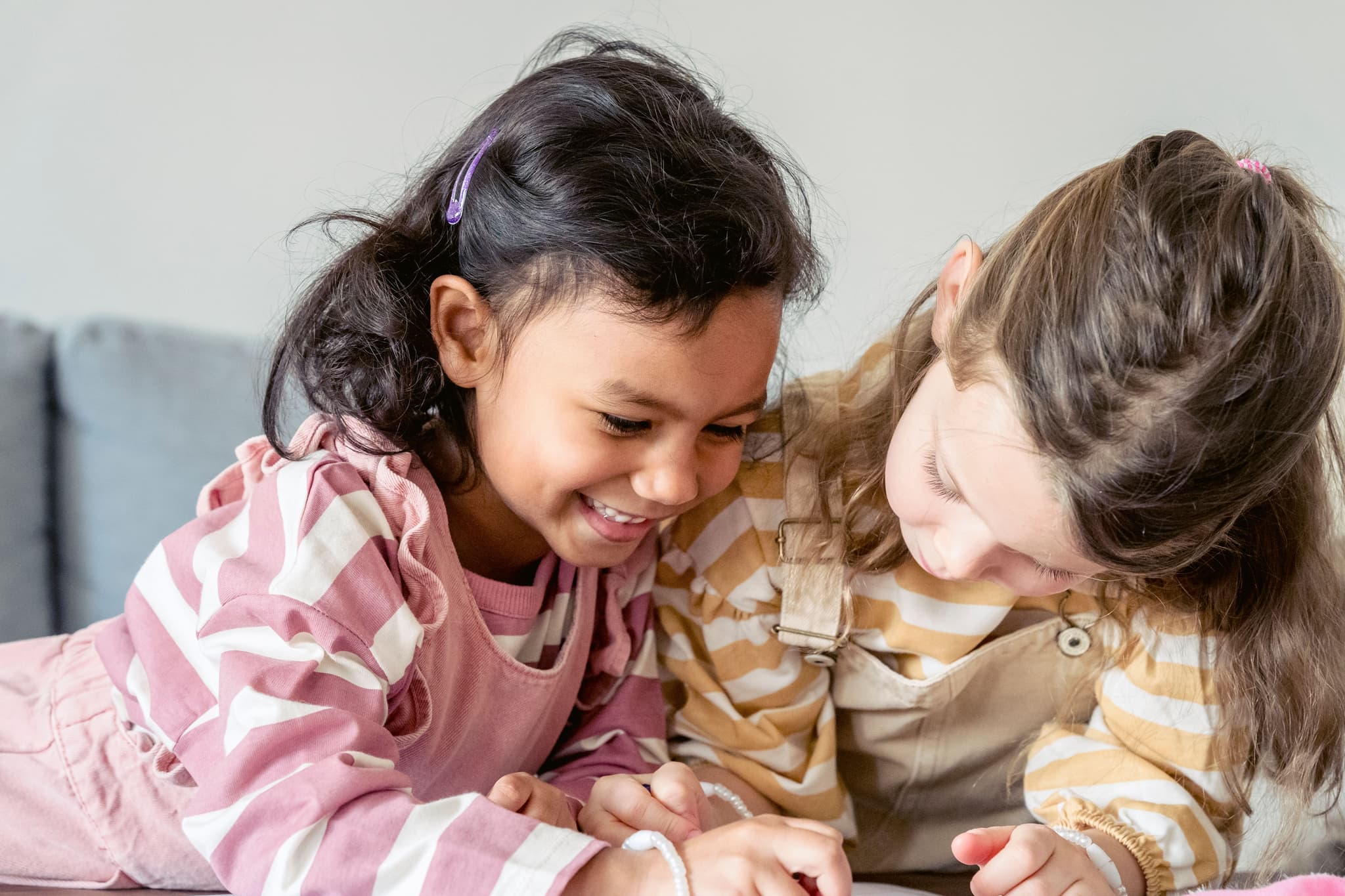Children Playing Together Indoors Two children smiling and playing together indoors on a light background.