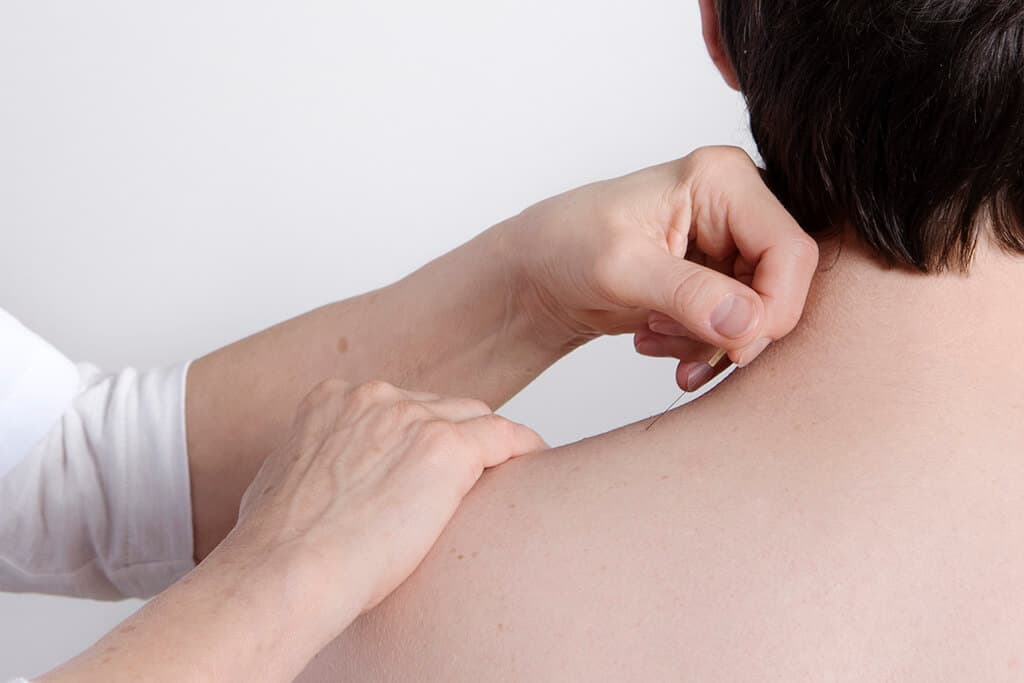 Hands examining skin assessment Two hands examining the skin on a person's shoulder during a medical or dermatological examination.